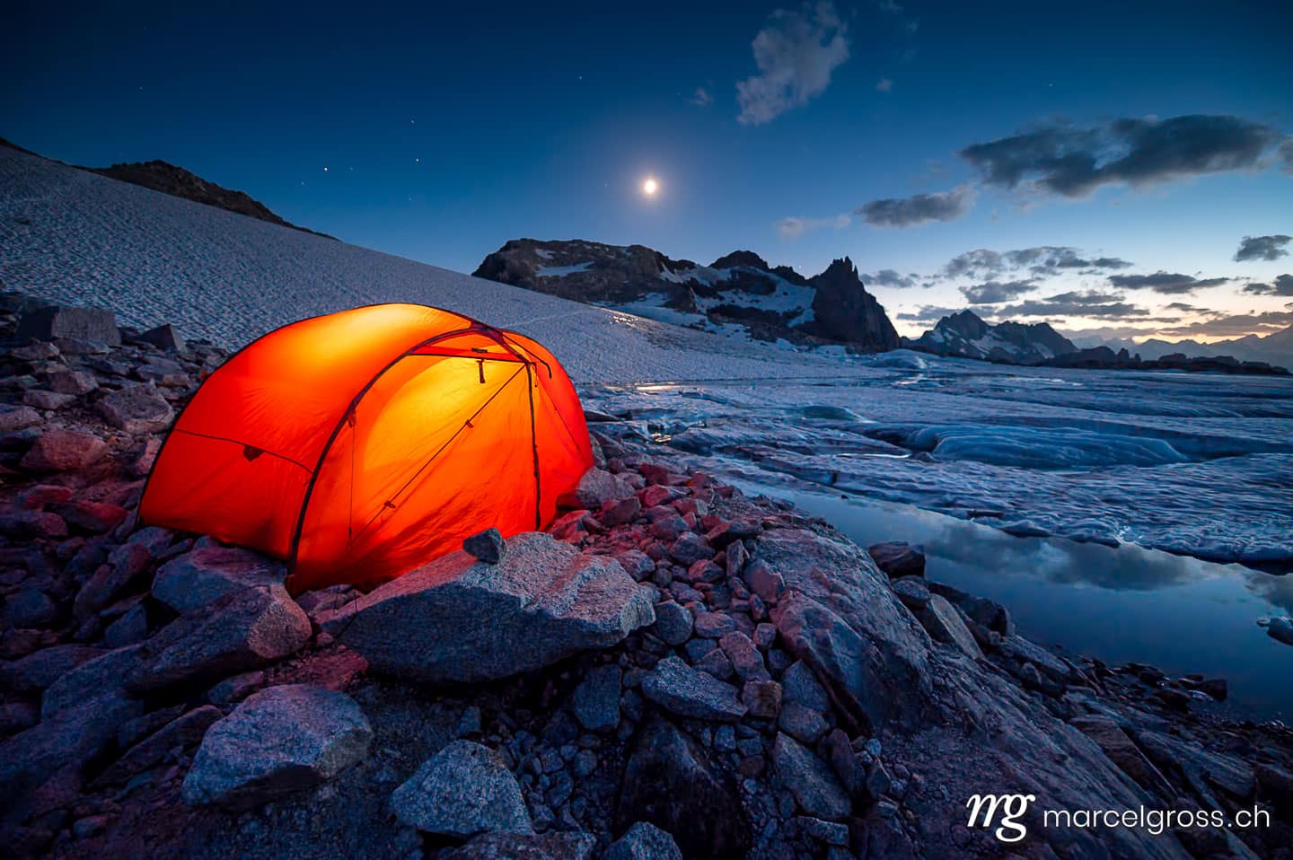 Panoramabilder Schweiz. red tent camping at a glacier lake in the swiss alps. Marcel Gross Photography