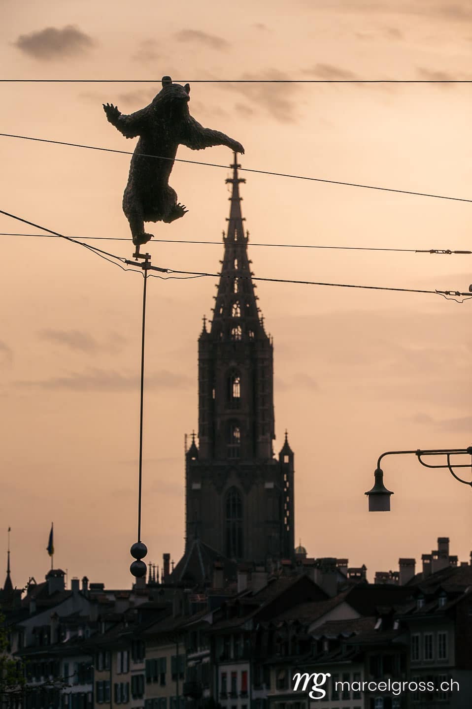 Bern Bilder. bear statute over the silhouette of Berner Münster near Bärengraben. Marcel Gross Photography